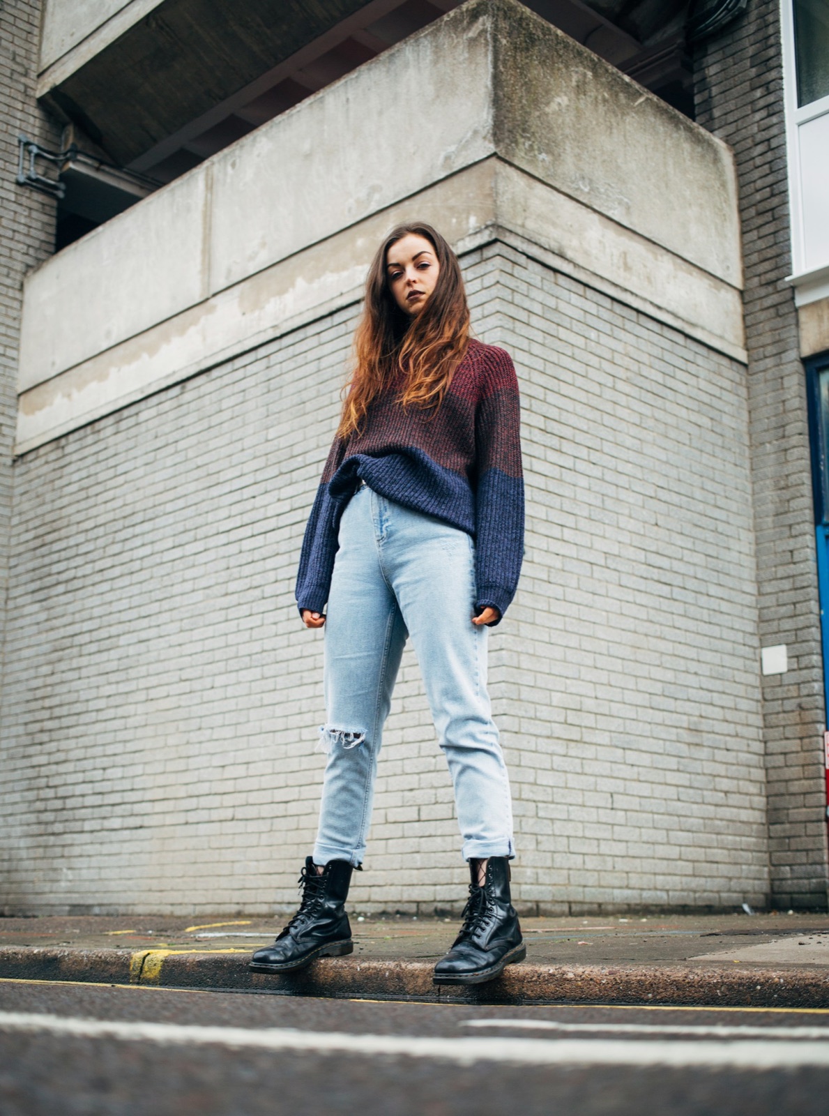 Fit check example: a woman in a colour-block sweater, light jeans and black boots standing on a street